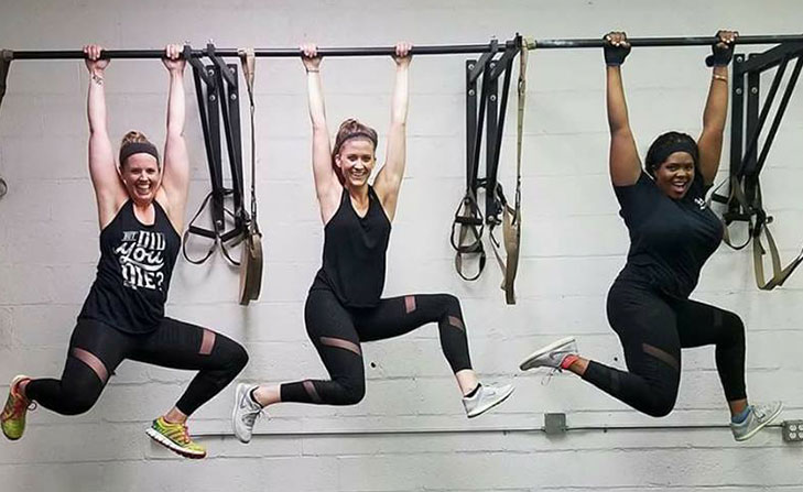 Three women doing pull ups.